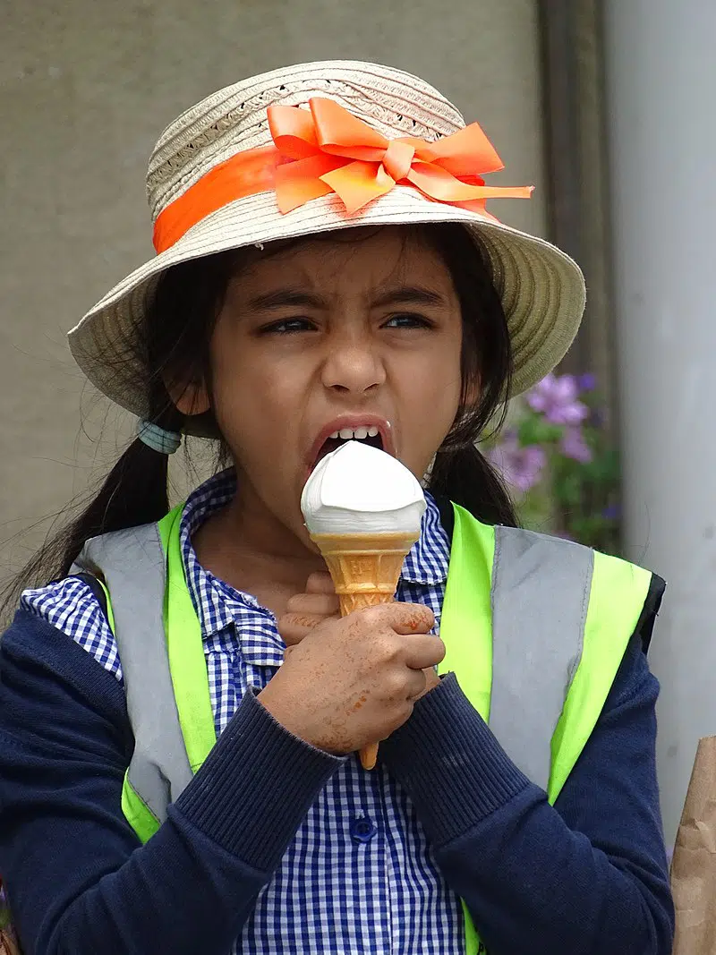 Een jong meisje dat haastig ijs consumeert, een veelvoorkomende oorzaak van ijshoofdpijn of brainfreeze