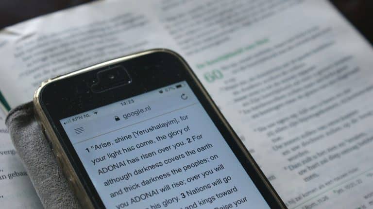 De afbeelding toont een mobiele telefoon, mogelijk een iPhone, die een webpagina weergeeft met tekst, een Bijbeltekst. Mobiele telefoons zijn draagbare apparaten die draadloze communicatie mogelijk maken via een mobiel netwerk.