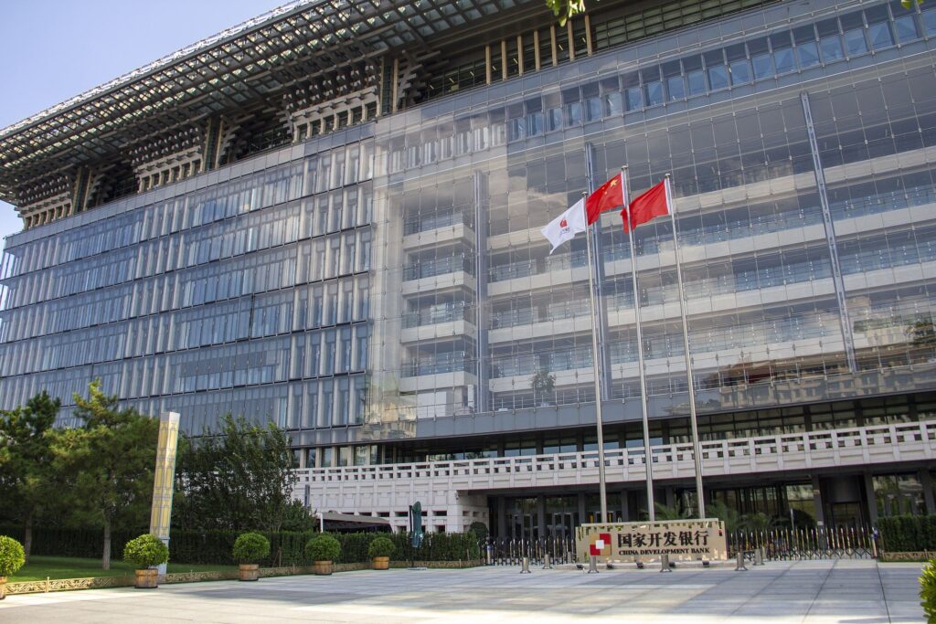 Hoofdkantoor van de China Development Bank in Beijing, met moderne glazen gevel en Chinese vlaggen voor het gebouw.