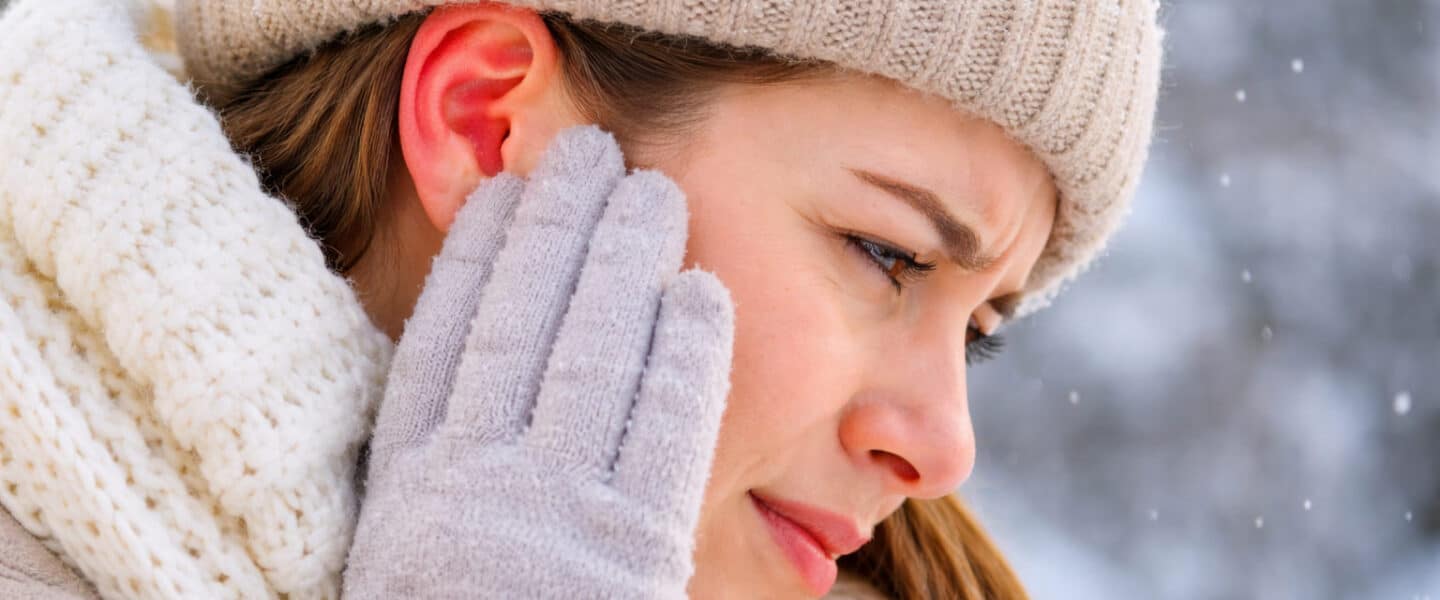 Vrouw met rode en pijnlijke oren door kou, passend bij winteroren tijdens winterse omstandigheden