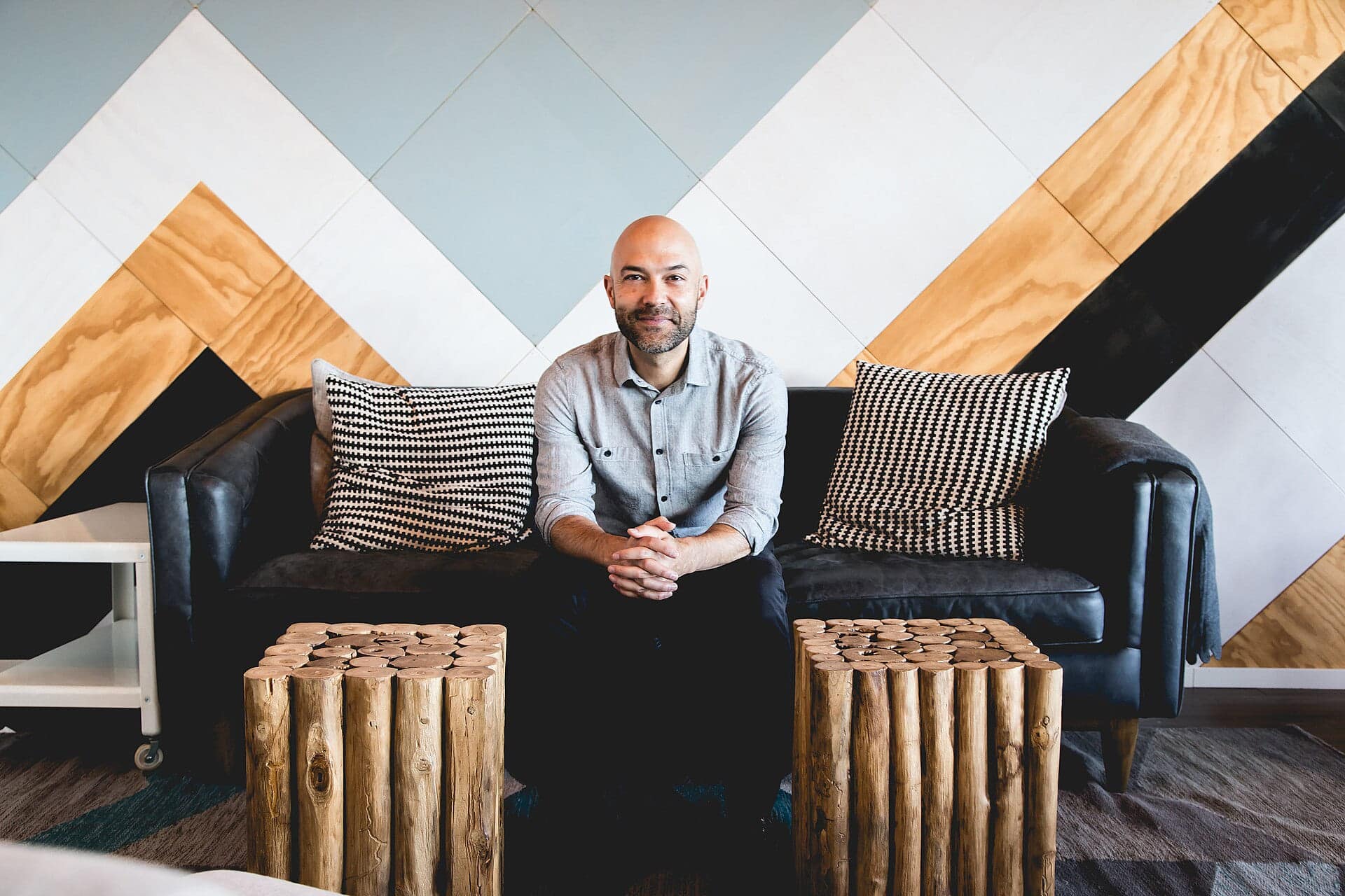Portretfoto van Joshua Harris, voormalig evangelicaal auteur en voorganger, zittend op een zwarte bank in een modern interieur.